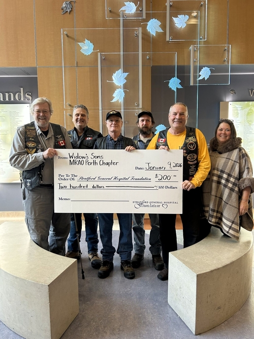 Members of the Widows Sons Masonic Riders Association of Ontario — Perth Chapter stand with a foundation representative inside Stratford General Hospital, holding a ceremonial cheque for $200 in support of the Stratford General Hospital Foundation. Several members wear motorcycle vests with patches, reflecting the group’s riding association and community service mission.